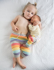 Kids laying down on bed in rainbow cloth diaper
