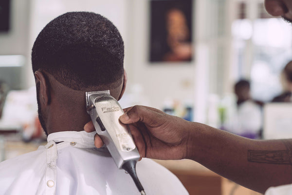 person holding hair clipper cutting the hair of man sitting