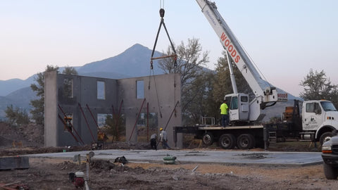 crane installing tilt-up concrete walls for modern utah home