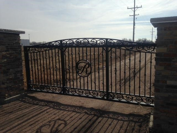 Decorative cantilever gate with scroll work that resembles thorns. There is a large "R" in the middle of the cantilever gate