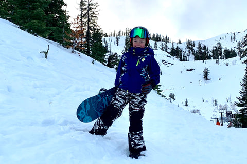Kid standing with snowboard