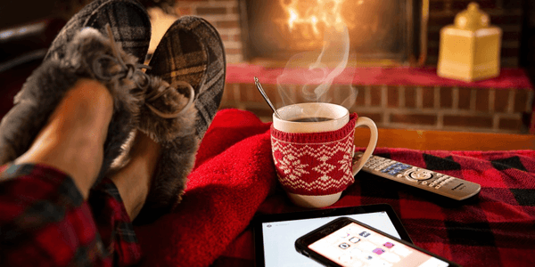 Example of a person lowering stress levels by sitting near a warm fireplace with a cup of hot chocolate.