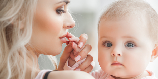 Baby touching a cold sore on the lips of an infected person.