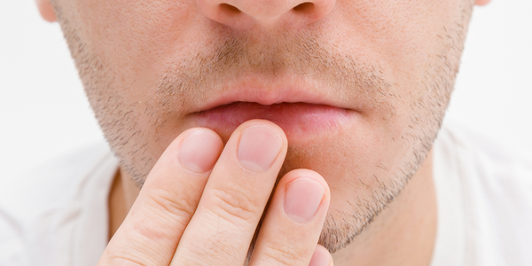 A man touching his lips wondering if the tingle feeling indicates a cold sore.