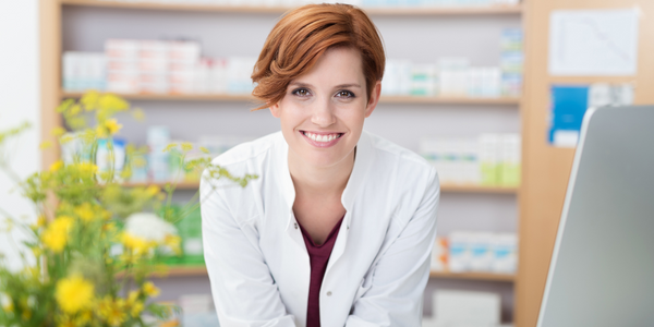 Pharmacist standing behind a pharmacy counter.
