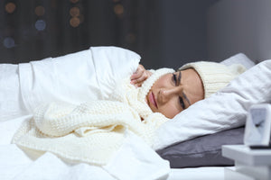 Woman cold in bed with winter clothing on
