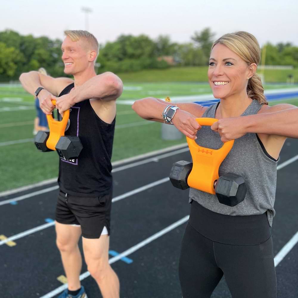 Two athletes working out with Kettle Gryp at a running track