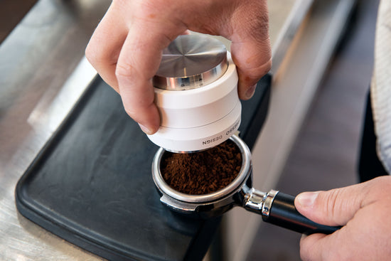 A barista using the white Artpresso distribution tool