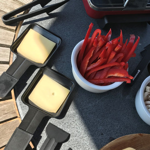 raclette cheese in dishes ready to melt under raclette grill