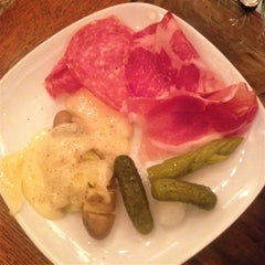 Raclette cheese over boiled potatoes, salami, prosciutto and pickled asparagus and cucumber
