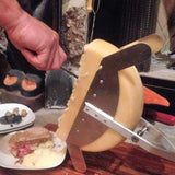 Raclette cheese being scrapped off the wheel