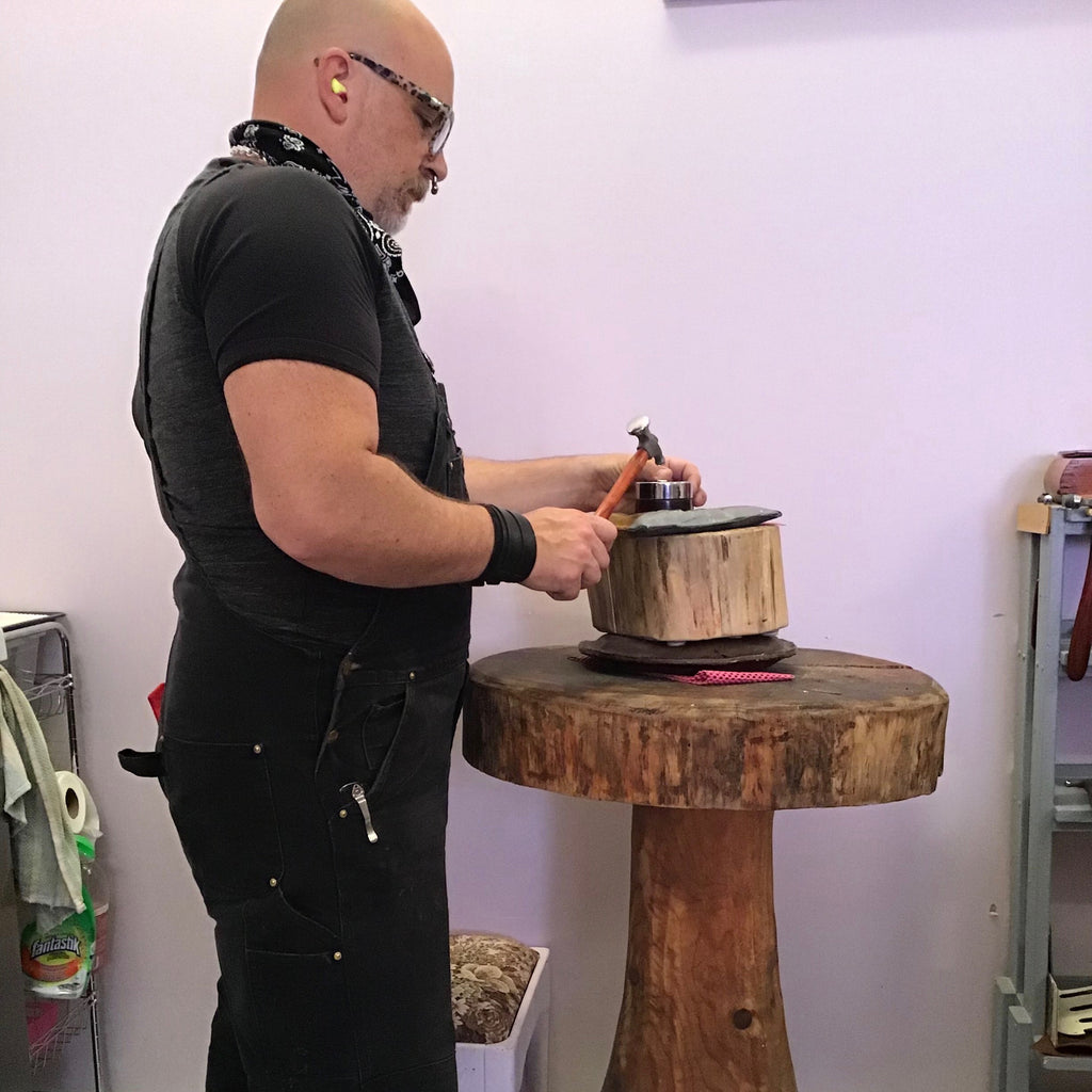 Inside a jeweller's studio, a virtual tour.  Kelly from Mikel Grant Jewellery using a Fretz hammer to texture silver on awesome wooden stump.