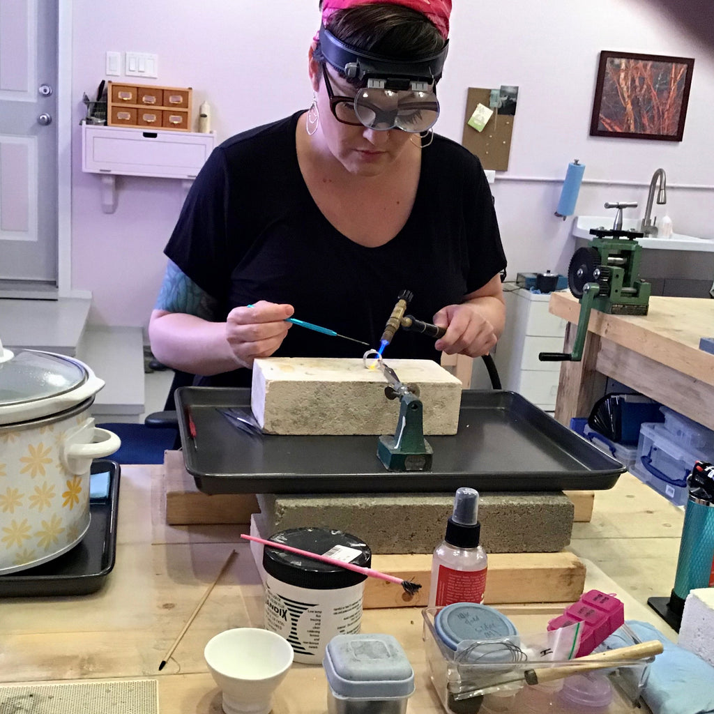 Inside a jeweller's studio, a virtual tour.  Mikel from Mikel Grant Jewellery soldering at workbench.  