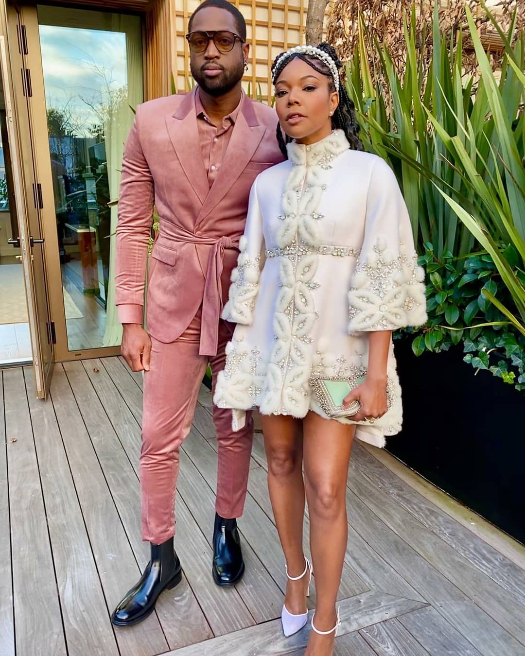 Hollywood American actress voice artist activist author Gabrielle Union attended the Ralph & Russo Paris fashion week show  husband American former professional basketball player Dwyane Wade Mae Cassidy, Botanical Mint & Silver Zeenat Clutch bag handbag ⁣Stylist Thomas Christos styled intricately detailed white couture Ralph & Russo cape dress Lilac court shoes Kenneth Soh Makeup and Hair pearl detail headband pink velvet layered look tie-waist slim-fit trouser suit shirt white socks black leather pull-on boots sunglasses. Botanical Mint Moonstone Lilac Coral Dreams Power Pink silver antique gold