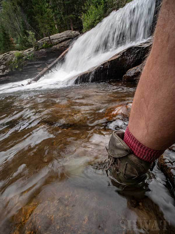 Boots in river by waterfall