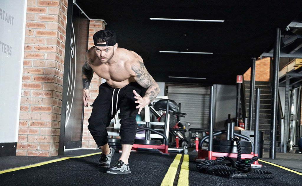 athletic man with tattoos working out in gym