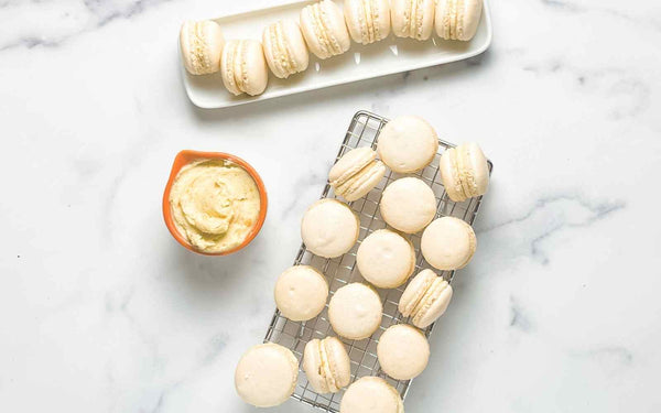 green cardamom macarons with vanilla bean butter cream on kitchen counter top