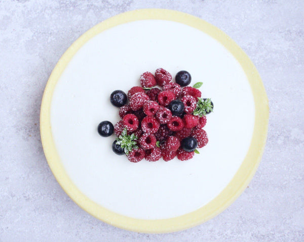 white chocolate cheesecake topped with an assortment of fresh berries and herbs