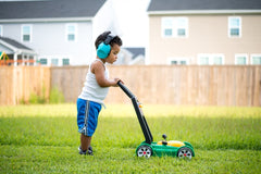 Toddler mowing the lawn with a play mower