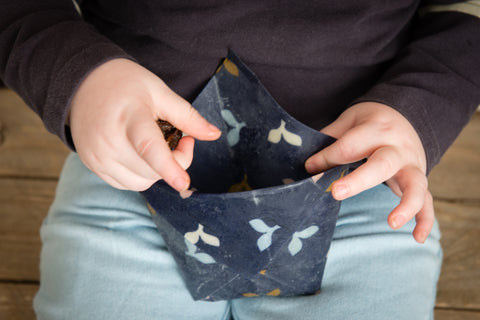 child holding beeswax wrap pouch full of sultanas