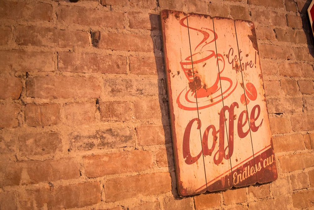 coffee sign that says get more coffee hanging on brick wall