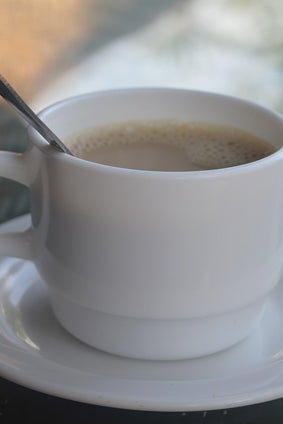 cafe au lait in a white cup with spoon