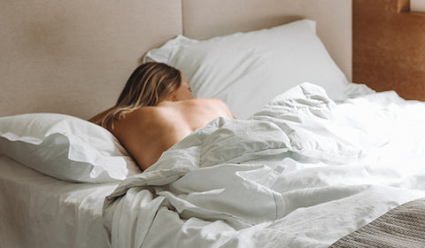 Woman sleeping on stomach in bed without a bra