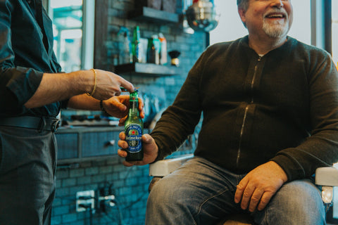 Claudio the barber giving a Heineken 00 to one of his clients at Fade Room barbershop