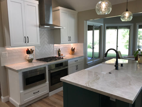 Bicycle Glass Pendant Lighting Lunar 768 in clear with single pendant hardware kits in black, hang straights in black over a modern green kitchen island, lights on, close-up shot featuring white cabinets, stainless steel appliances and open bay windows