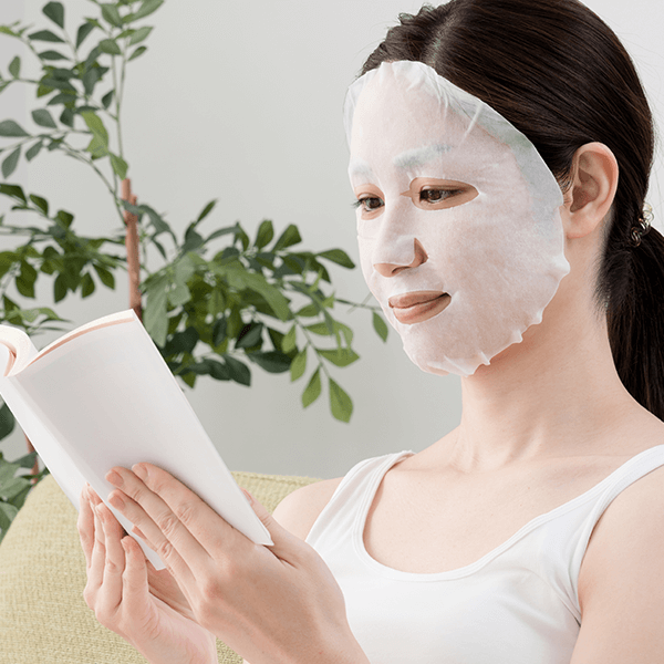 woman wearing sheet mask reading a book