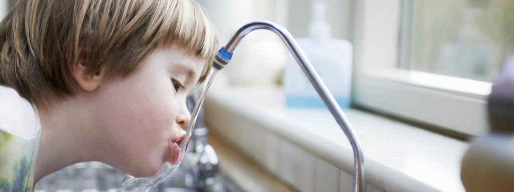 Un enfant boit au robinet une eau saine grâce au filtre purificateur d'eau pour robinet CLEAN.WATER
