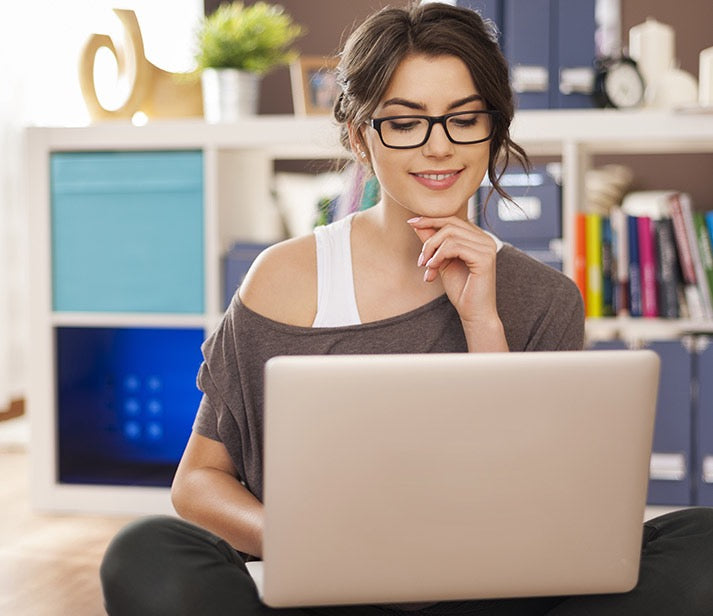 Une femme, devant son ordinateur, utilise les lunettes de repos Stop Fatigue pour ne pas abimer ses yeux.