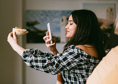 A woman poses with her food as she takes a selfie.