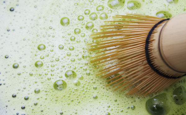  A matcha brush soaked within a bowl of matcha.