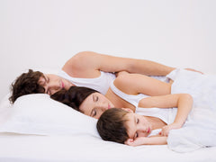 Natural-family-sleeping-together-white-sheets