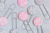 group of neon pink bookmarks and black and white bookmarks scattered over grey background