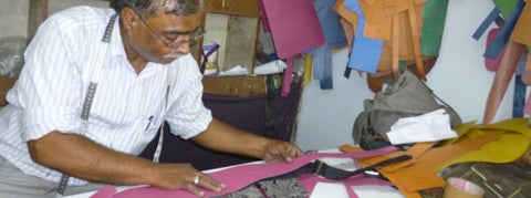 A patter cutter in aour fair trade factory in delhi making ethical bohemian travel belts and festival outfits
