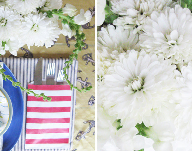 white carnations and cutlery in a red and white striped pocket