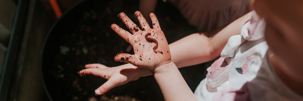 a child's hand with dirt and a worm on it