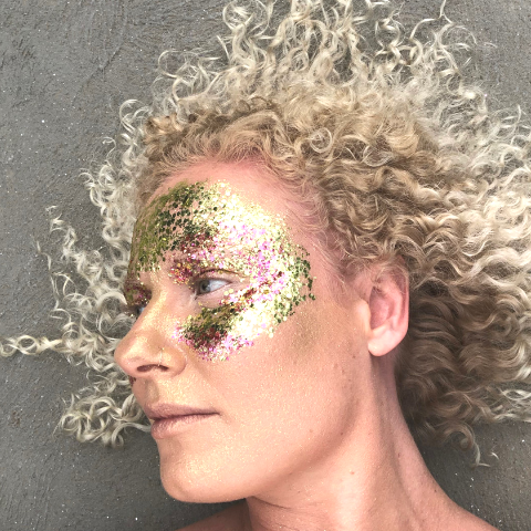 Emily Shurey co-founder glitterazzi wearing mask of gold and pink glitter