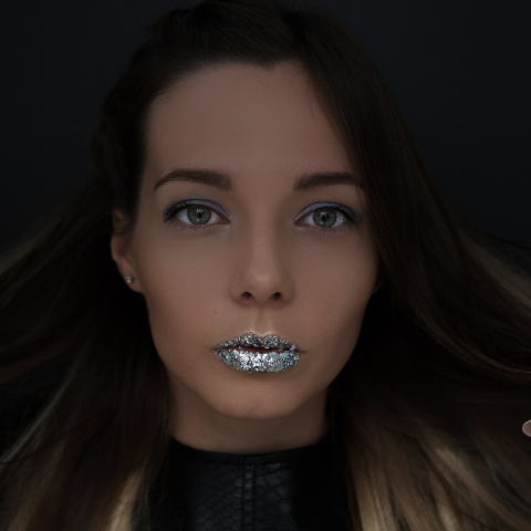 Lady wearing sliver glitter on her lips in a dark room 