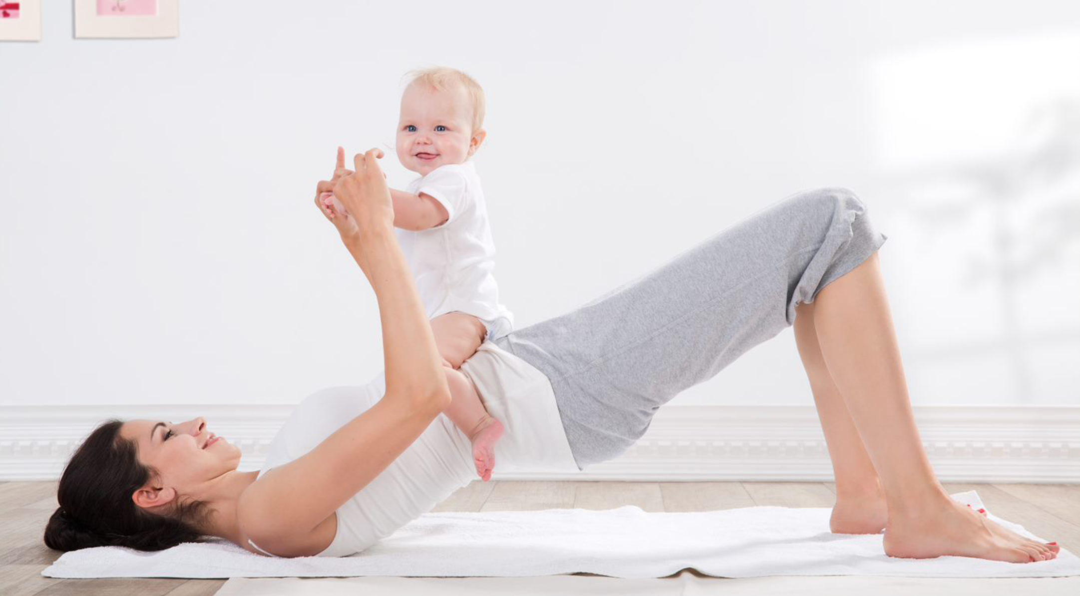 Mom doing yoga with baby sitting on top of her 