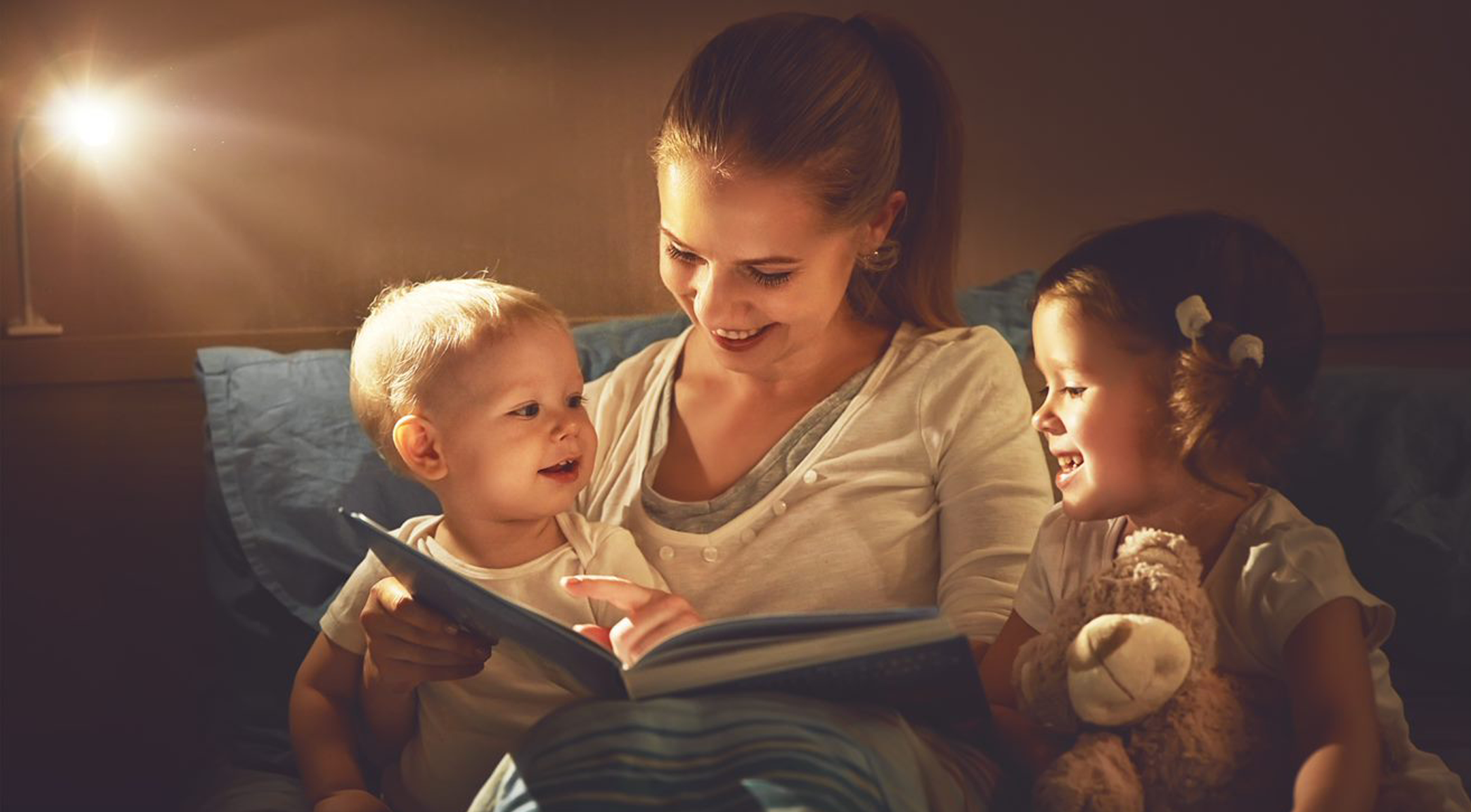 Mom with her two kids reading a book before bed