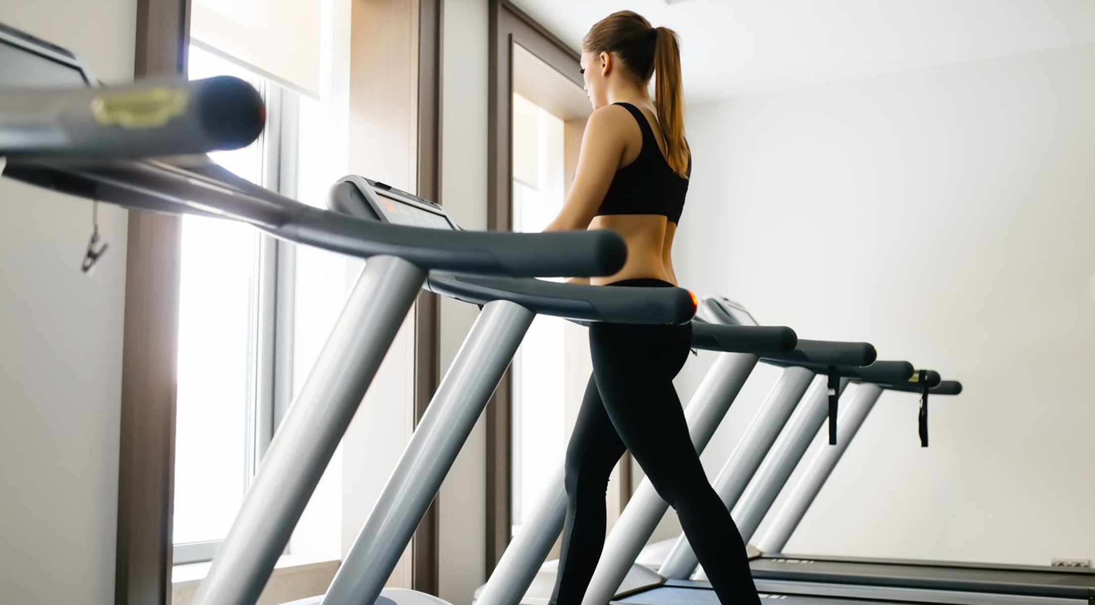 Woman from behind, walking on treadmill