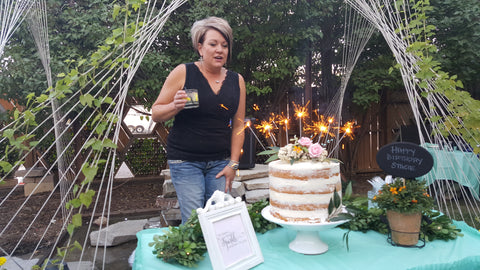 Woman posing outside infront of a birthday cake with 10-inch sparklers on it.