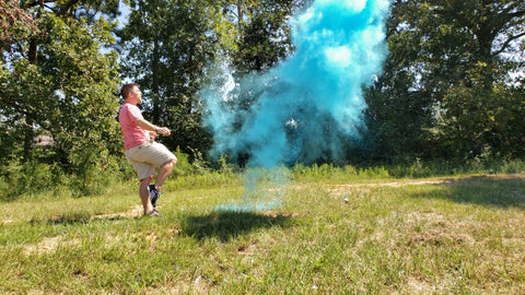 Individual kicking a blue smoke filled soccer ball, to celebrate having a baby boy.