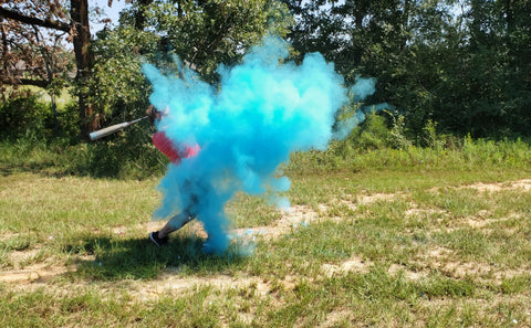 Individual hitting a blue smoke filled baseball announcing them having a baby boy