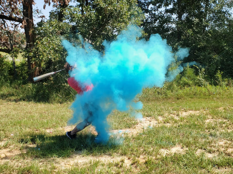 individual hitting a baseball full of blue smoke to announce having a baby boy.