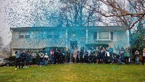 Family shooting blue confetti to announce their baby boy.