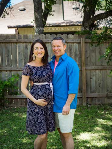 Couple posing outside in front of a wooden fence.